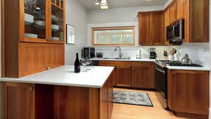 Una cocina moderna con armarios de madera, encimera blanca, electrodomésticos de acero inoxidable y una ventana sobre el fregadero.