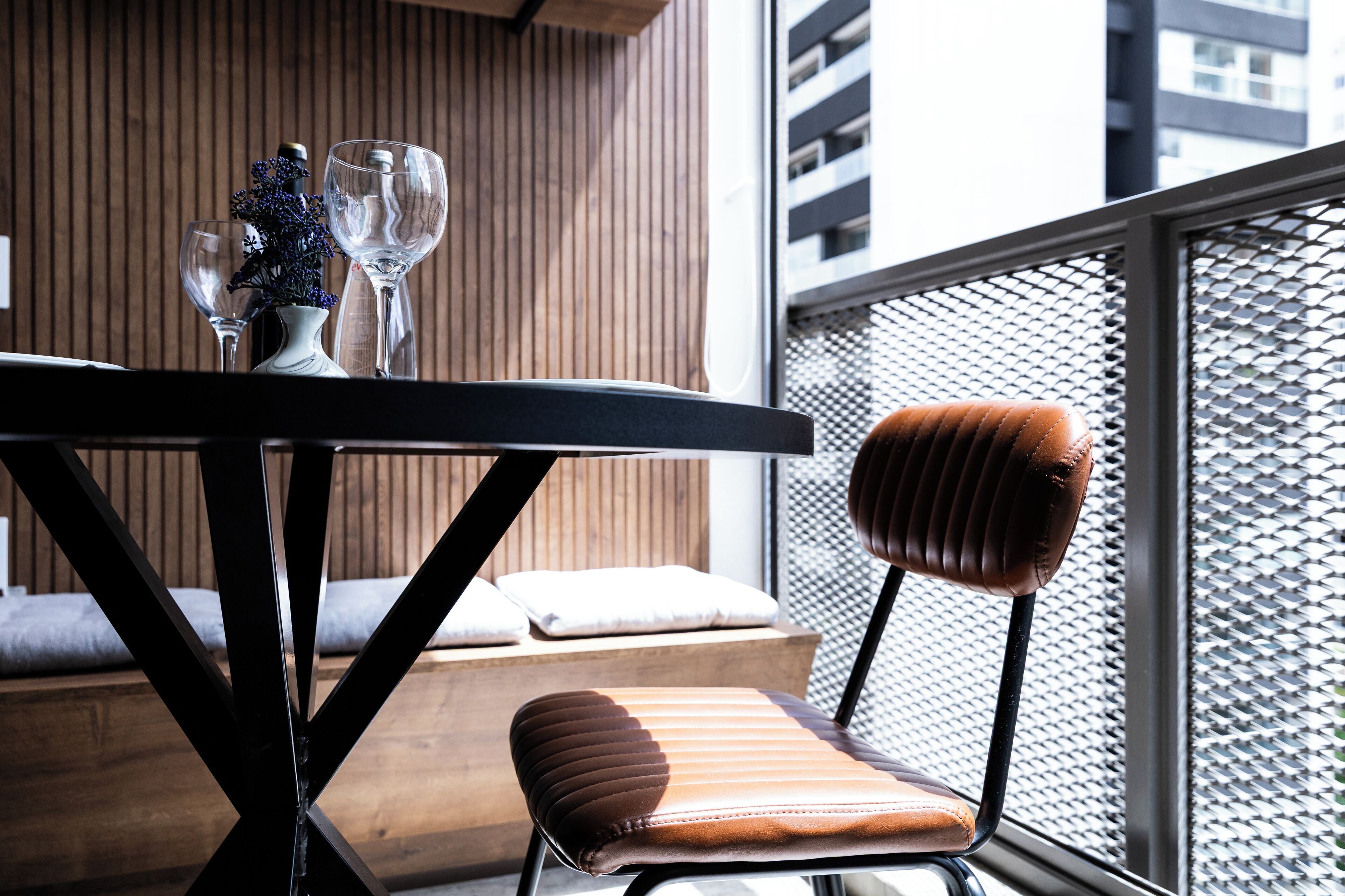 A modern dining area with a table, two chairs, and a vase with flowers.