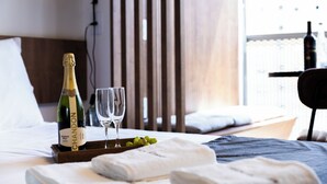 Habitación de hotel con una cama, una botella de Chandon, dos copas y una bandeja con uvas.