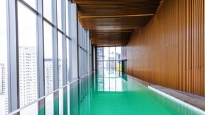 Una piscina techada larga y estrecha con techo de madera y grandes ventanales en un lateral.