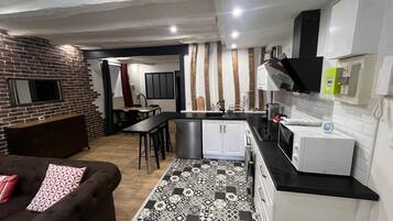 A compact kitchen with white cabinets, a black countertop, and a patterned backsplash.