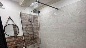 A modern bathroom with a glass-enclosed shower, a round mirror, and a white sink. - Apartment rental Limoges (Limoges)