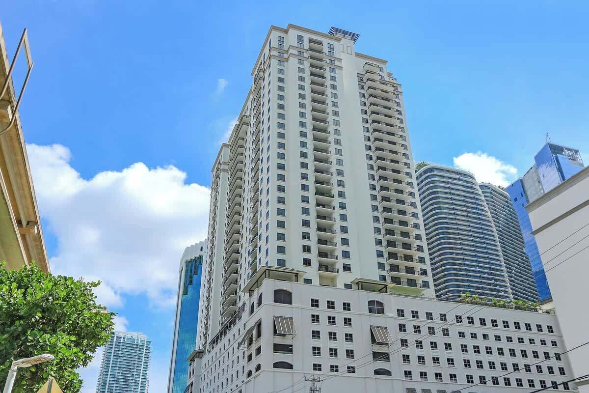 A high-rise building with multiple floors and balconies, surrounded by other tall buildings.