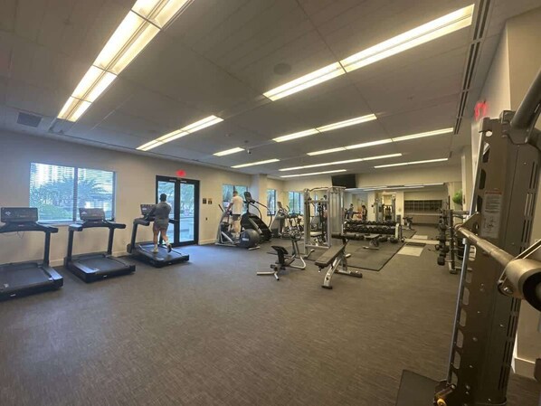 Un gimnasio con cintas de correr, elípticas y equipo de pesas.