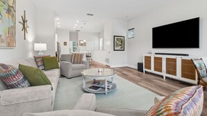 Una sala de estar moderna con sofá, sillones, una mesa de centro, televisor y un mueble aparador.