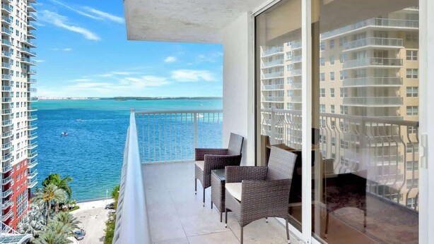 A balcony with wicker furniture overlooking a coastal view. - Newly Renovated 3BR Condo with Bay Views & Parking (Miami)