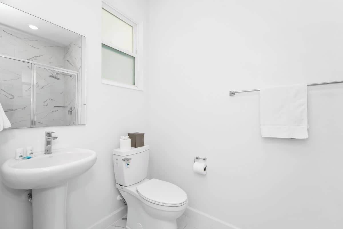 A modern bathroom with a white sink, toilet, and mirror.