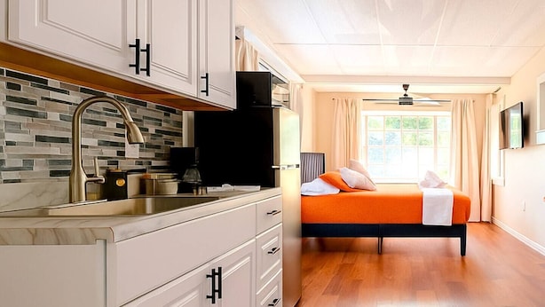 A modern bedroom with a bed, a built-in TV, and a large window with curtains.