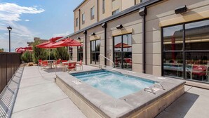 Una piscina con jacuzzi, mobiliario de exterior y sombrillas.