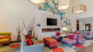 A modern living room with a flat-screen TV, colorful artwork, and contemporary furniture.