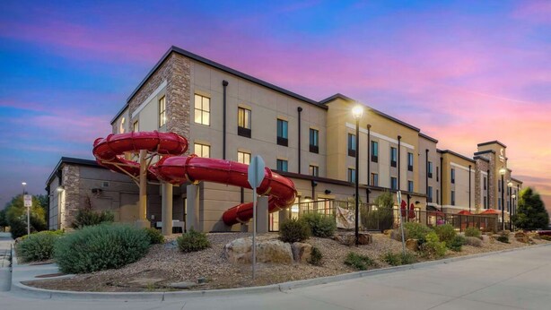 A hotel with a modern design, featuring a prominent water slide structure in front.