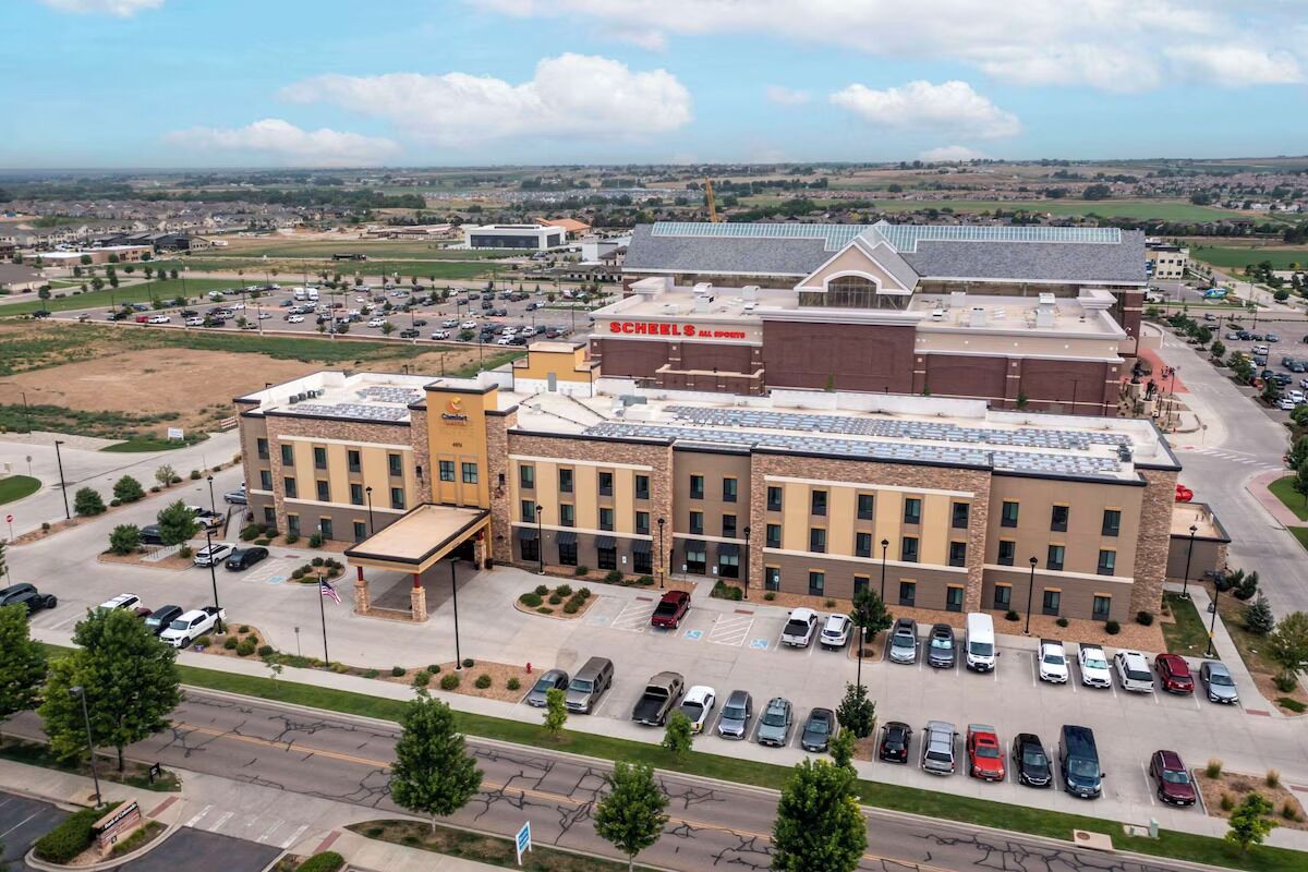 A multi-story hotel with a parking lot and a large building in the background.