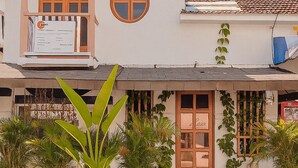 Een gebouw met een witte gevel, een houten deur en een balkon met een pergola.