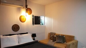 Een slaapkamer met een bed, een bank, een lamp en decoratie aan de muur.