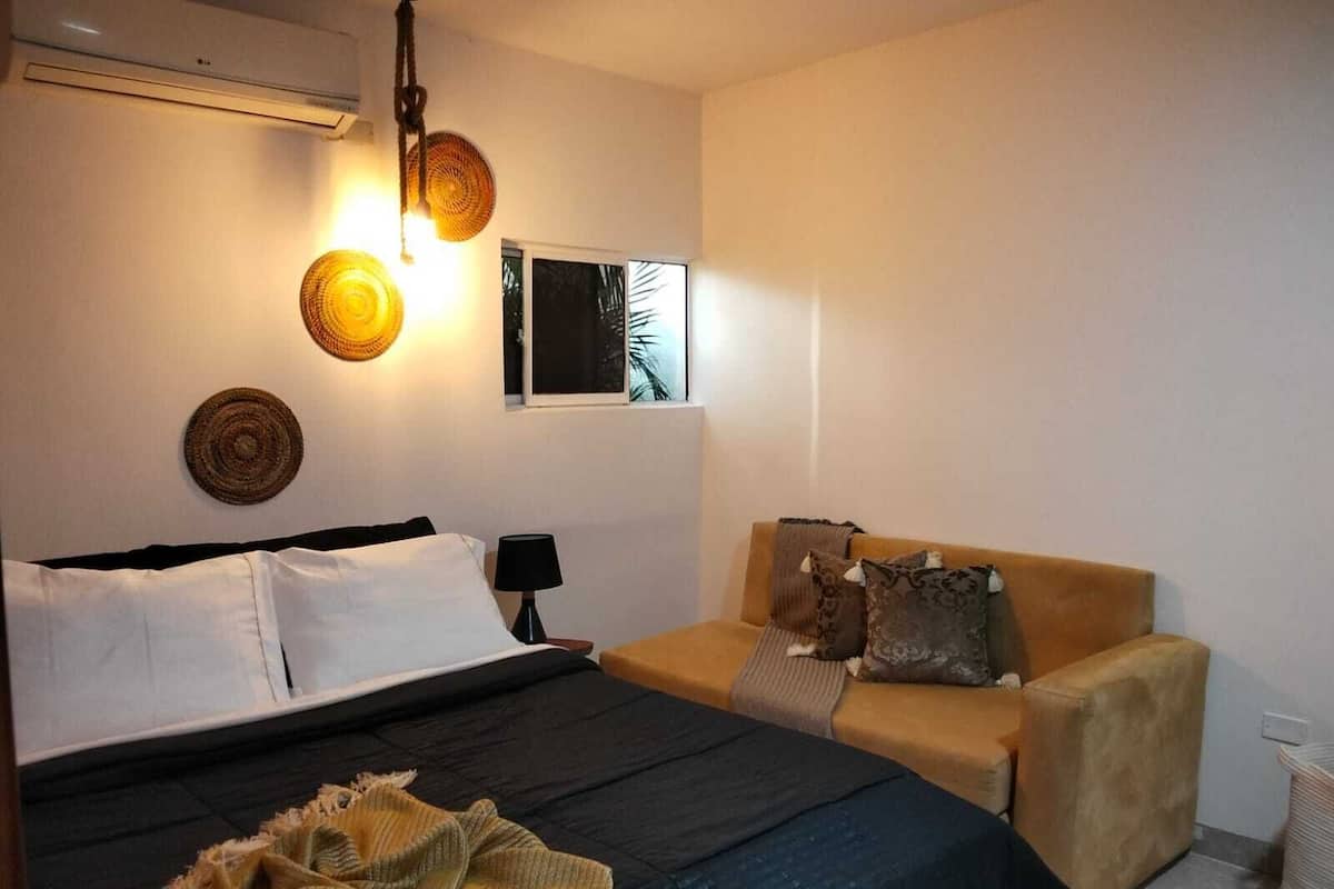 A bedroom with a bed, a sofa, a lamp, and wall decor.