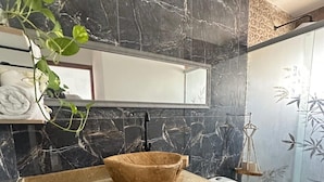 A bathroom with a marble backsplash, a wooden vanity, a white toilet, and a hanging plant. -  Hotel Tierra y Mar Boutique (Cartagena)