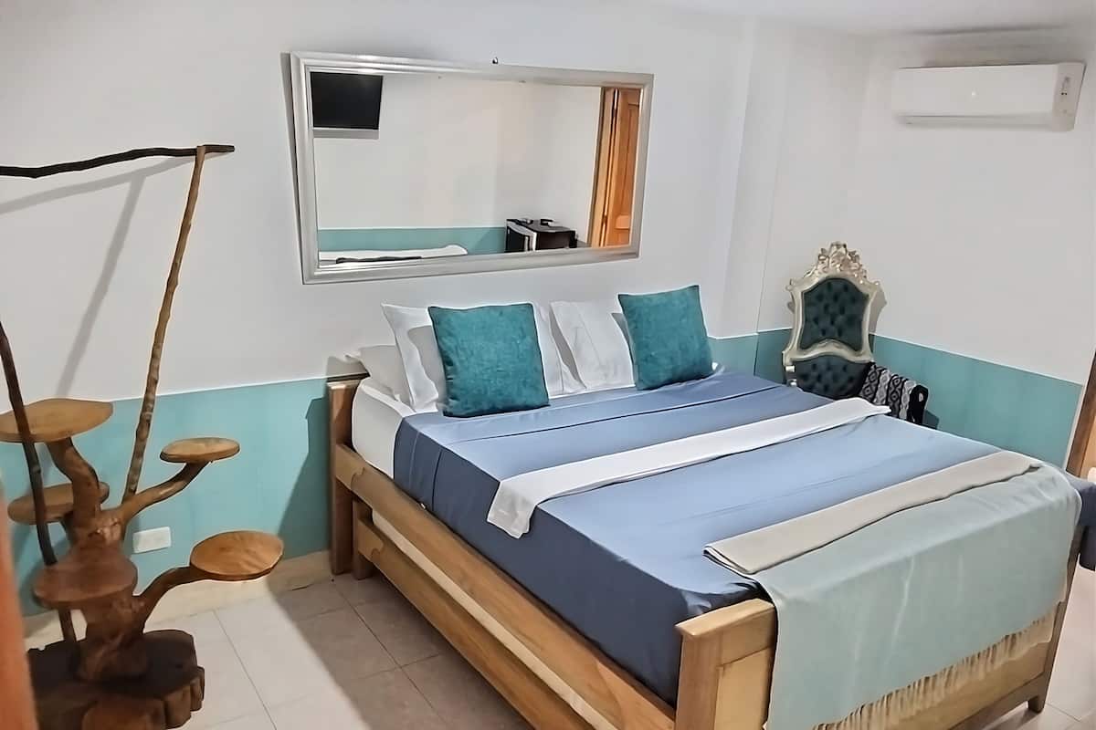 A bedroom with a bed, a mirror, and a wooden chair.