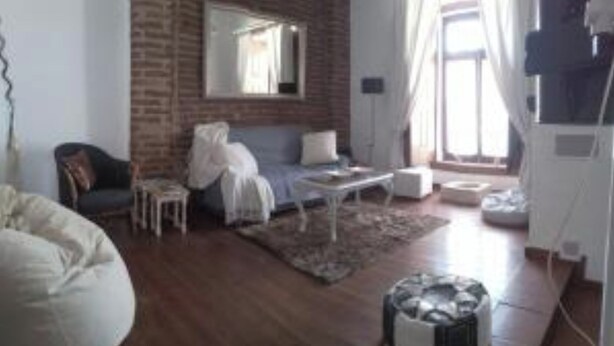 Ein Wohnzimmer mit Backsteinwand, einer Couch, einem Couchtisch und einem weißen Sessel.