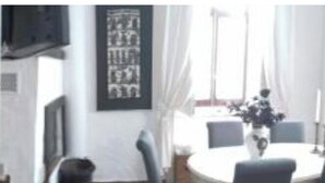 Ein Zimmer mit Backsteinwand, einem weißen Sofa, einem kleinen Tisch und einem Fenster mit Vorhängen.