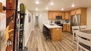 A modern kitchen with wooden cabinets, stainless steel appliances, and a central island with bar stools. - Location, location!  Spacious 4-BR double apartment near Cottonwood Canyons (Cottonwood Heights)