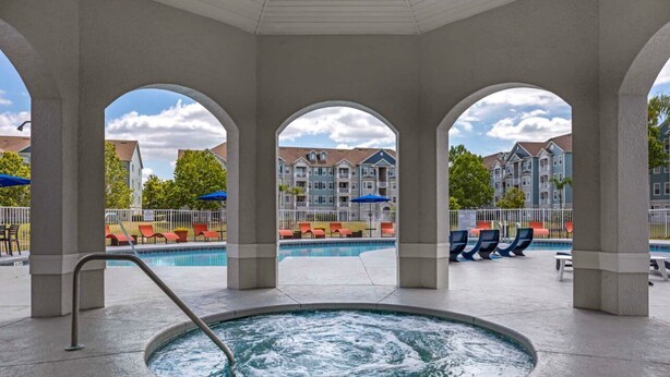 A pool area with a hot tub, lounge chairs, and a view of multi-story buildings. - 2 Ensuites Close to Disney Intertational Epic (kissimmee)