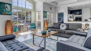A spacious living room with a grey sofa, a coffee table, and a large window. - 2 Ensuites Close to Disney Intertational Epic (kissimmee)
