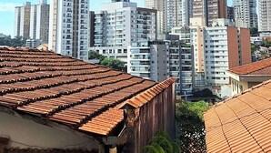 Un paisaje urbano con rascacielos y un techo de tejas tradicionales en primer plano.
