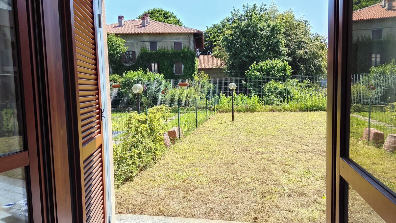 Vista de un patio trasero con una valla de madera, césped y una casa al fondo.