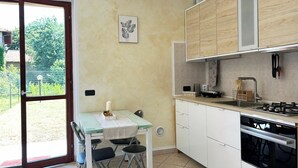 Une cuisine compacte avec un coin repas, une porte-fenêtre coulissante donnant sur l’extérieur et une vue sur la verdure.