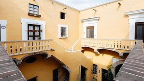 Un patio con edificios amarillos, arcos y balcones.