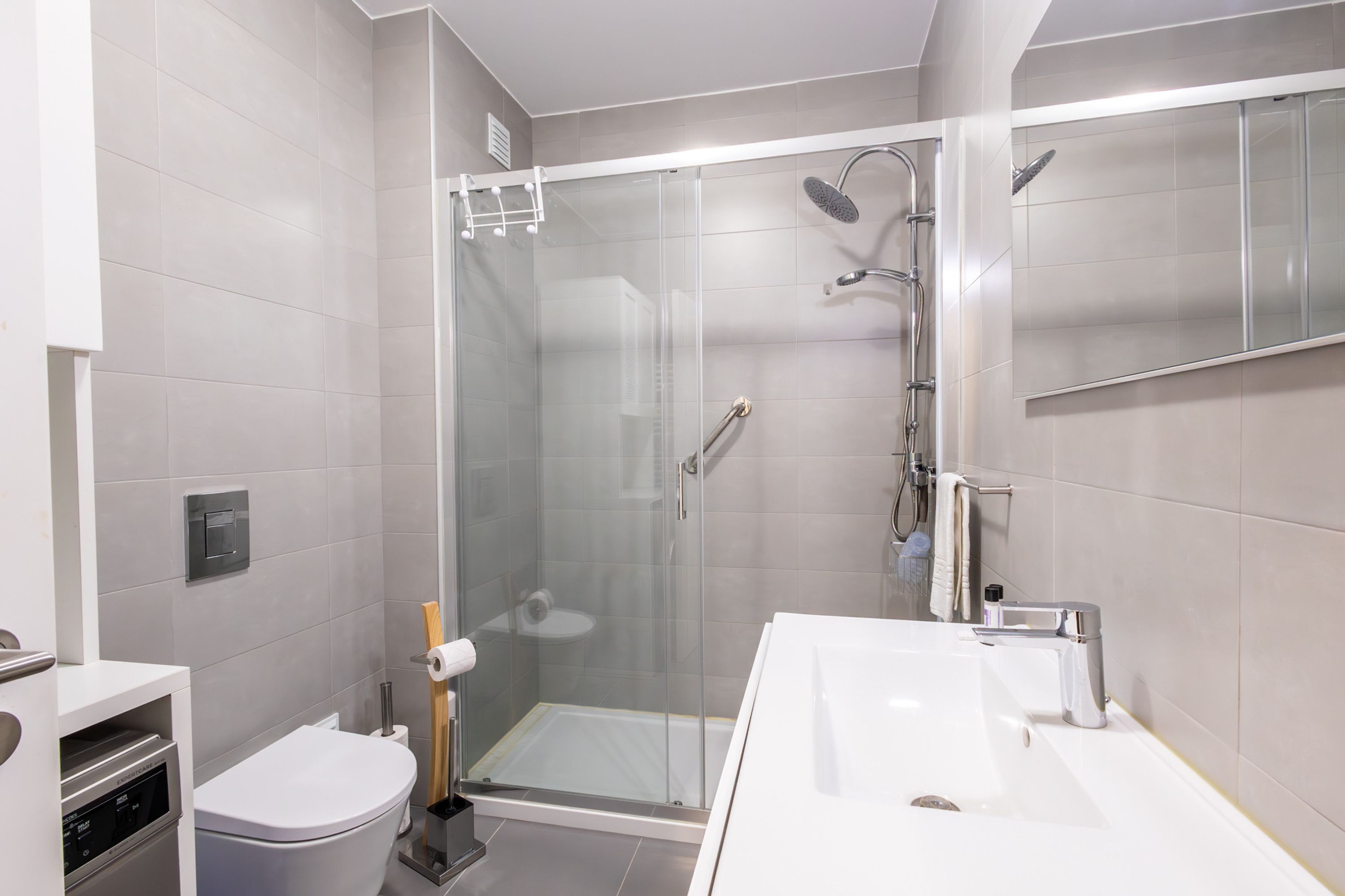Une salle de bain moderne avec une douche à parois de verre, un lavabo blanc et des toilettes.