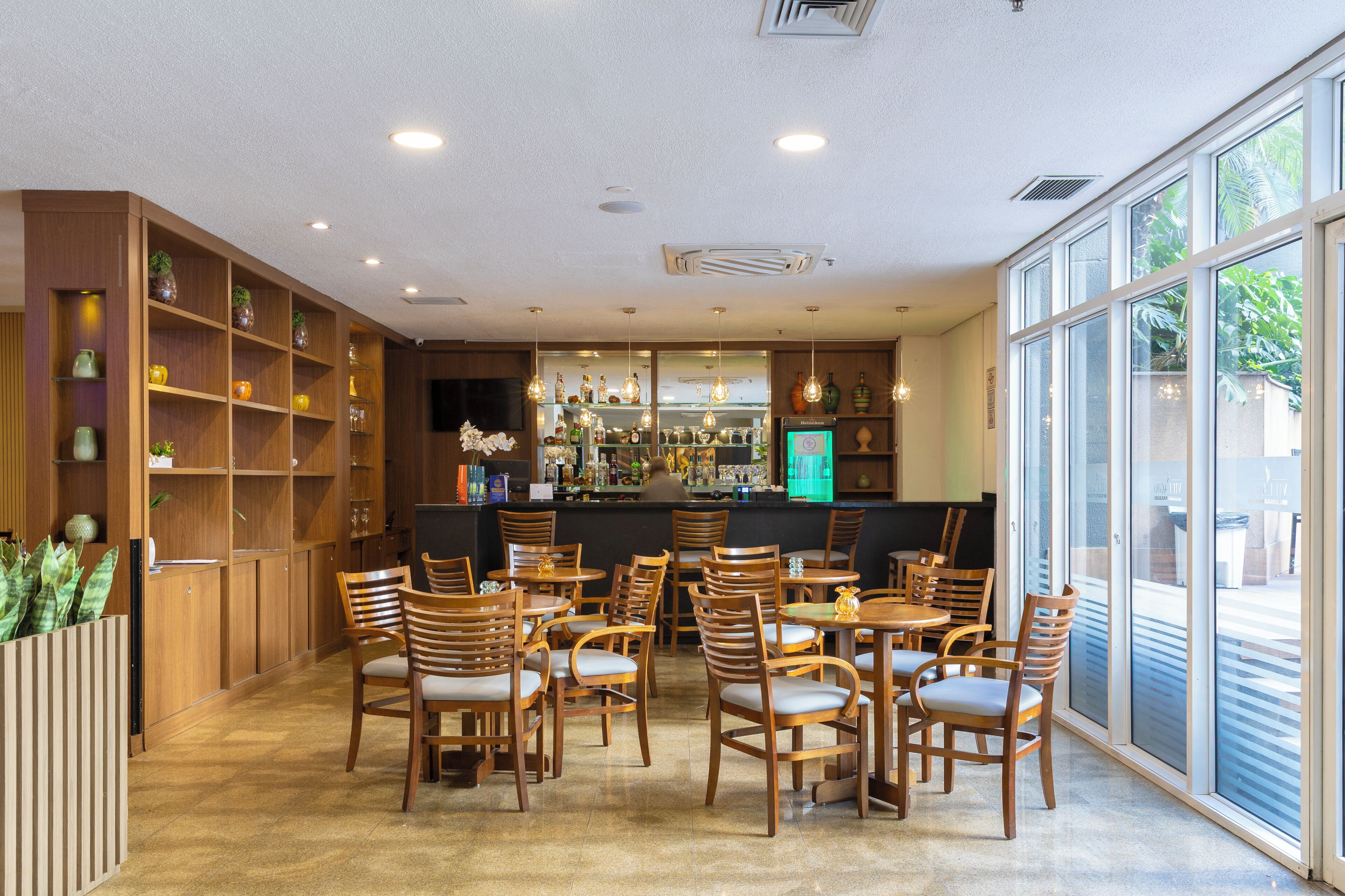 A cafe with wooden furniture, a bar area, and large windows.