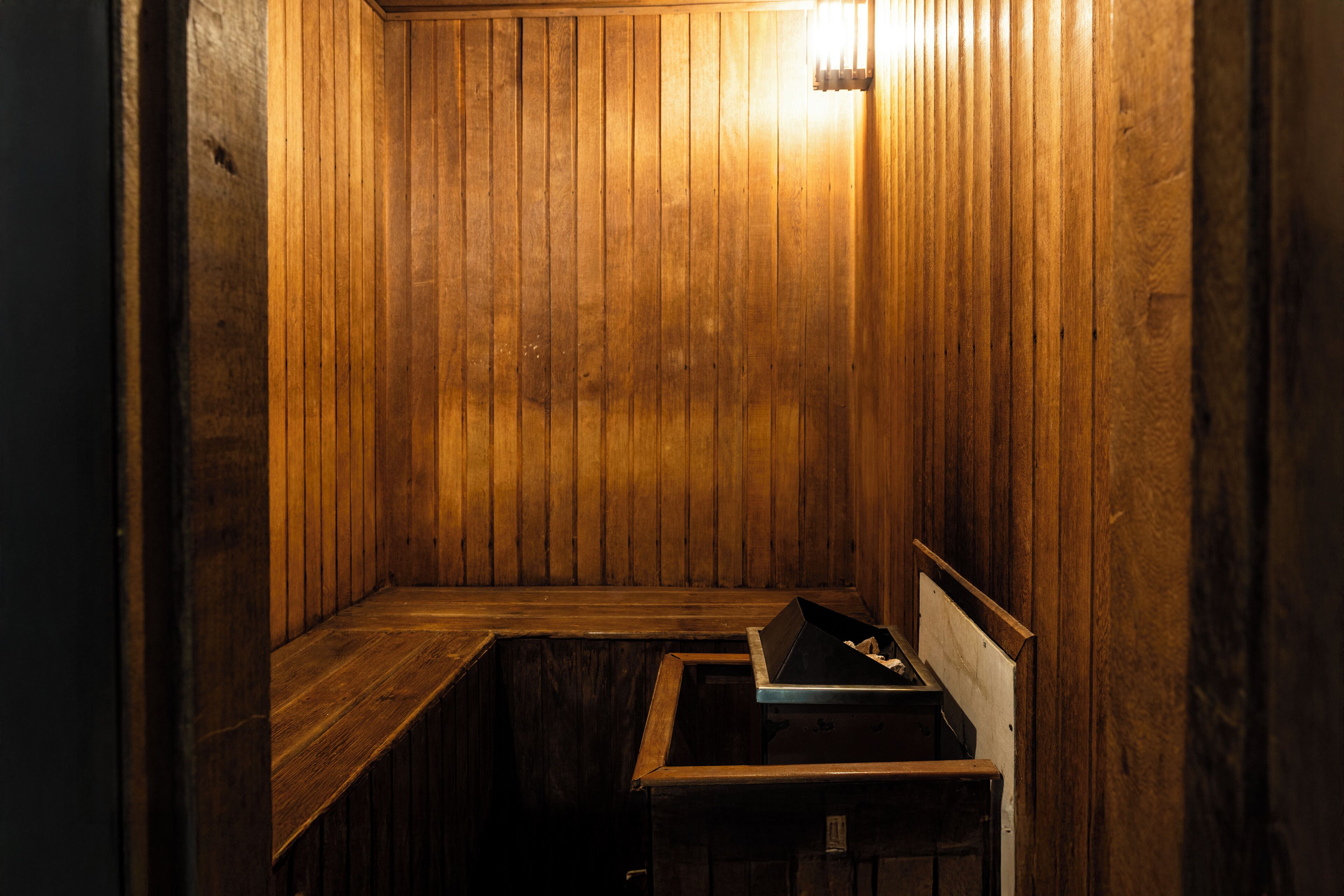 A wooden sauna with a bench and a small table.