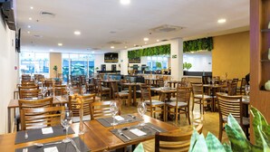 A restaurant with multiple tables and chairs, a bar area, and a view of the outdoors. - Próximo a Paulista com piscina  (Sao Paulo)