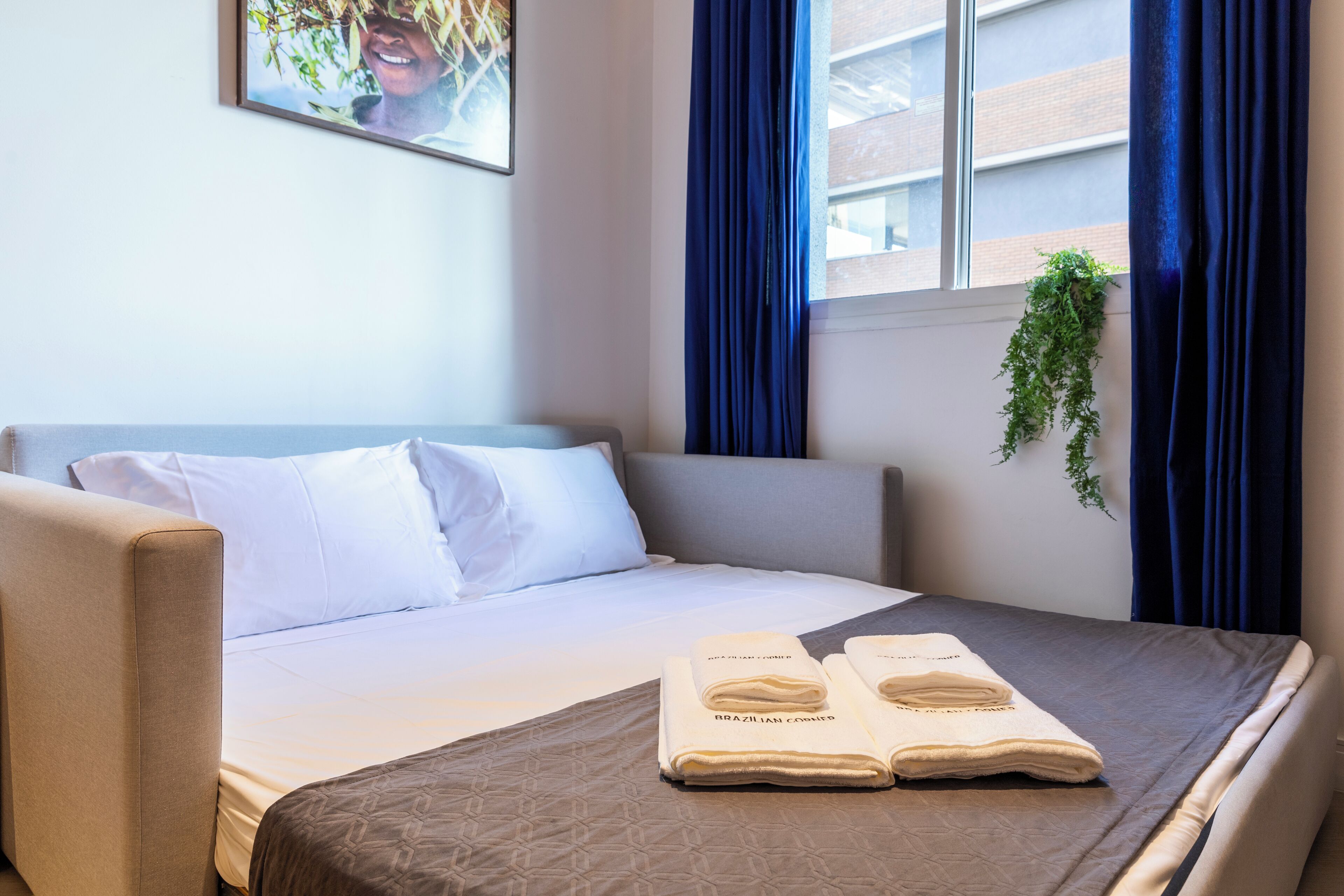 A neatly made bed with a brown bedspread and two folded towels with text on them.