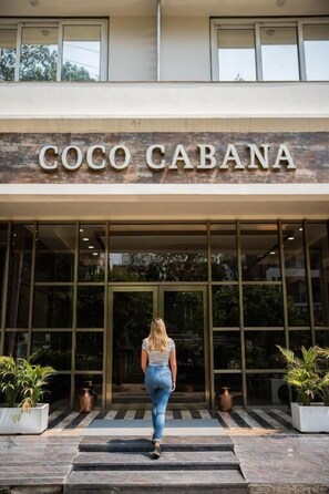The entrance to Coco Cabana with a woman walking towards it. - Goroomgo The Coco Cabana Varanasi (Varanasi)
