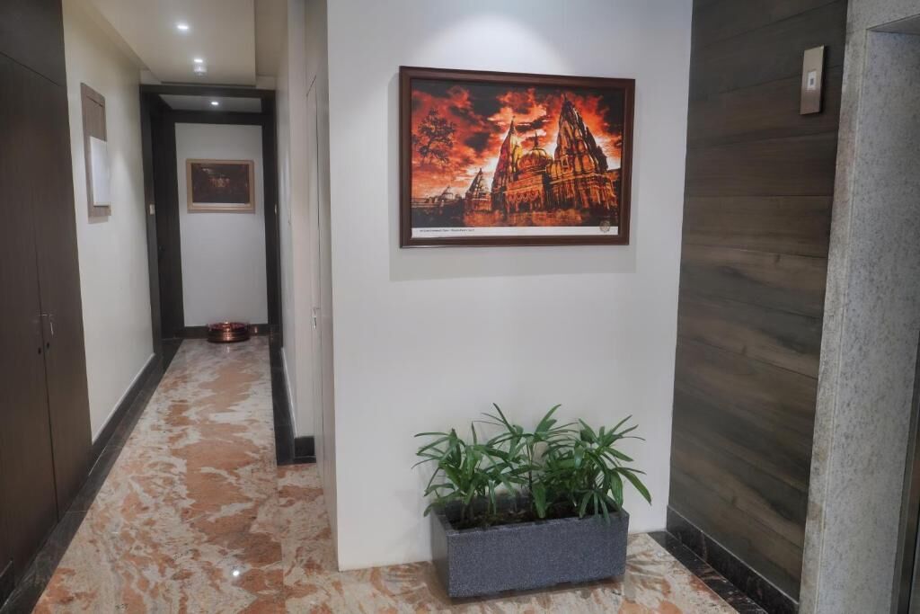 A hallway with a framed picture of a temple, a potted plant, and a dog bowl on the floor.