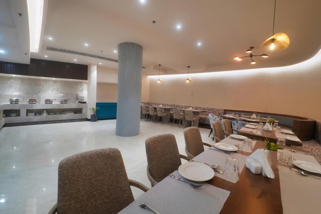 Un espace de restauration moderne avec un pilier central, des tables rondes et des chaises.