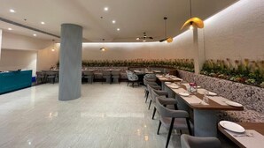 Un restaurante moderno con una barra larga, varias mesas y una pared decorativa con plantas.