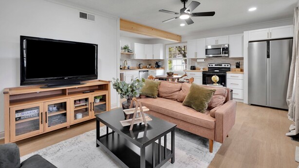 A modern living room with a flat-screen TV, wooden entertainment unit, and a black coffee table.