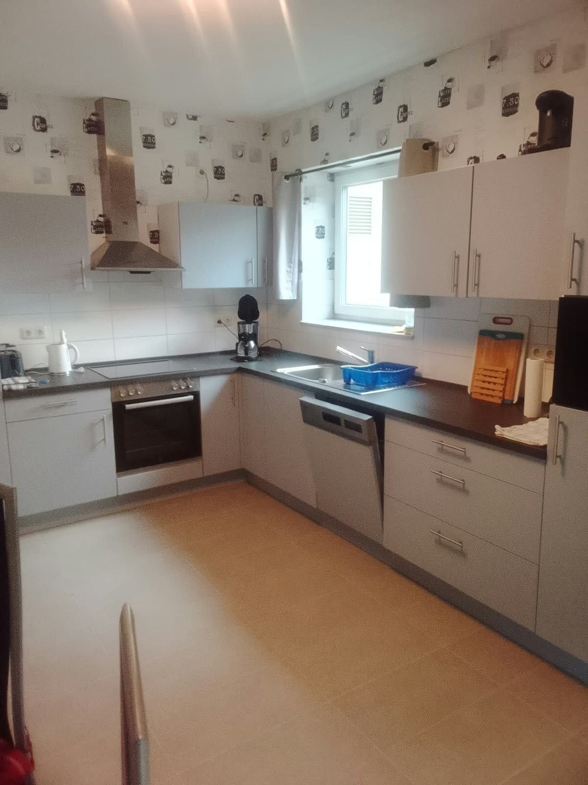 Eine kleine Küche mit Herd, Backofen, Spüle und einem Fenster für natürliches Licht.