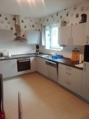 A compact kitchen with a stove, oven, sink, and a window providing natural light.