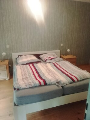A bed with a striped bedspread, two bedside tables, and a wall with a textured pattern.
