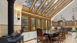 A spacious kitchen with a large dining table, wooden chairs, and a built-in wood stove. - 82 Lenawee Lane (Keystone)