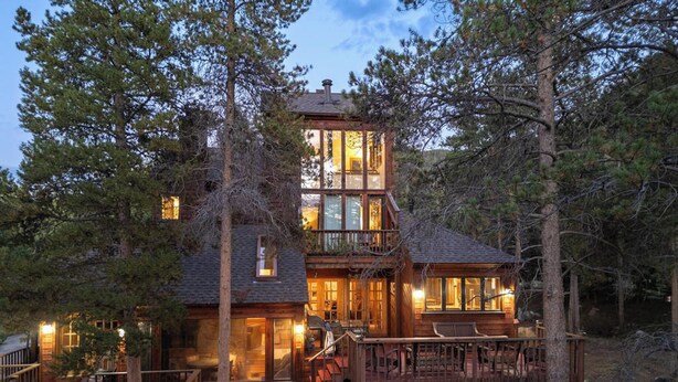 A two-story log cabin with a balcony, surrounded by trees. - 82 Lenawee Lane (Keystone)