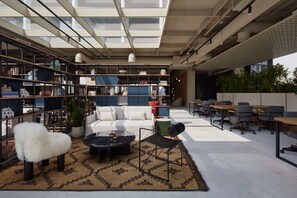 A modern office space with a central seating area, bookshelves, and a large window providing natural light. - Deluxe Studio with Balcony Full Burj Khalifa View (Dubai)
