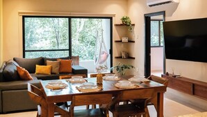 A modern living room with a sofa, dining table set for four, and a large flat-screen TV. - Peace Family Vacation Home, Swimming Pool, Barbecue Grills and Gym (Playa del Carmen)