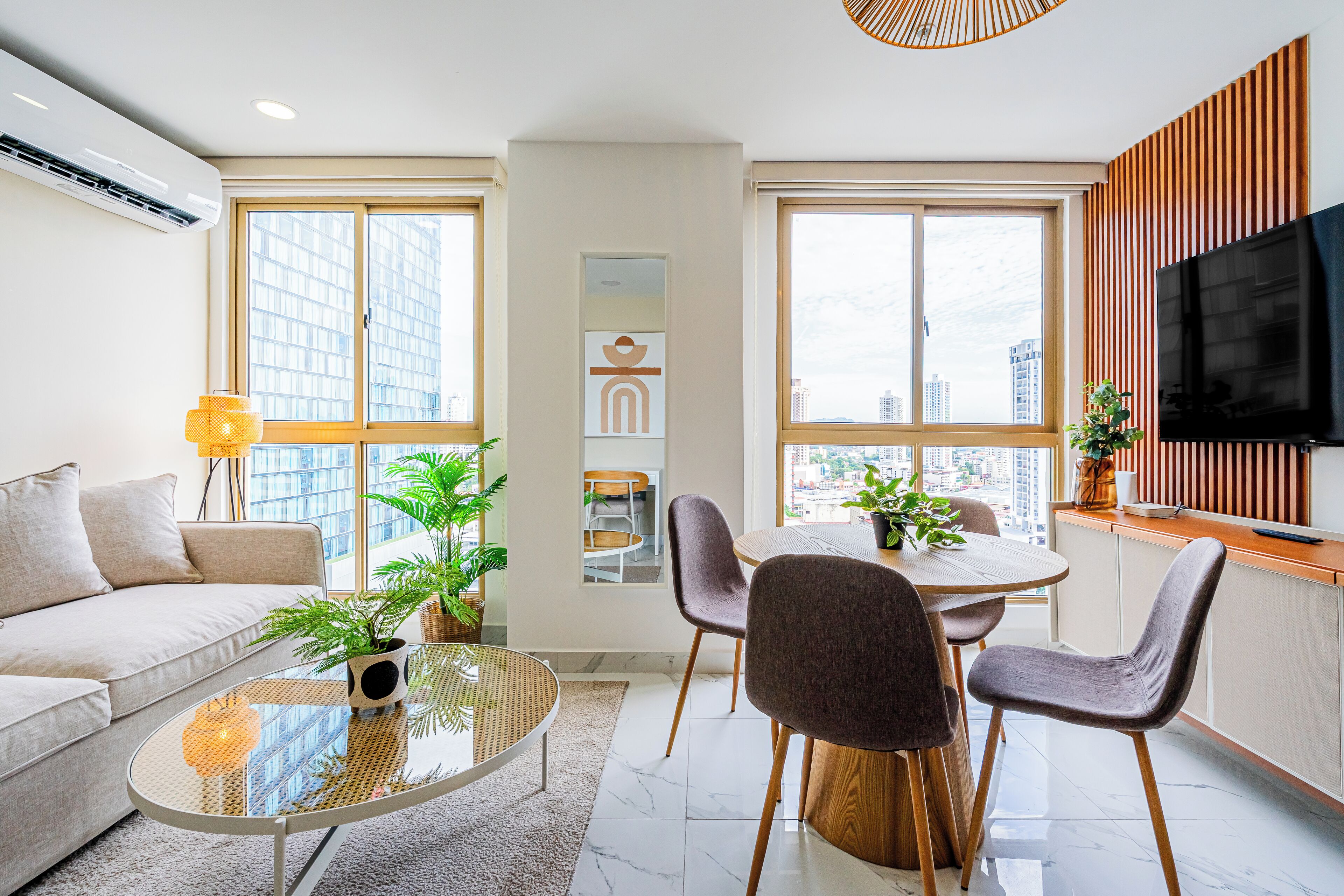 A modern living room with a sofa, a glass coffee table, and a dining area with chairs and a table.