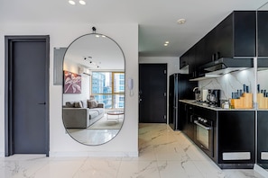 A modern kitchen with black cabinets, a marble countertop, and a built-in oven. - Mini Design By Wynwood House (Panama City)