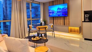 Una sala de estar moderna con un televisor de pantalla plana, un comedor con mesa redonda y una cocina con cafetera.